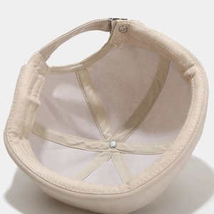 Inside view of beige cotton docker hat showing six-panel stitch and metal buckle