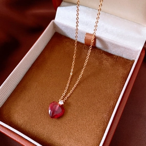 Close-up of a vintage golden heart pendant necklace with red gemstone in a luxury box