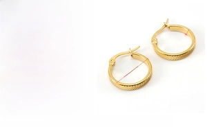 Detail of gold U-shaped titanium steel earrings featuring unique diagonal textured finish