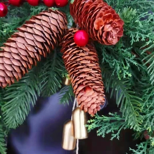 Close-up macro detail of a rustic Christmas wreath with pine cones and golden bells