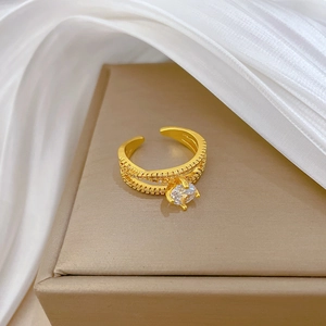 Adjustable gold plated twisted ring with sparkling zircon stones on a luxury jewelry box