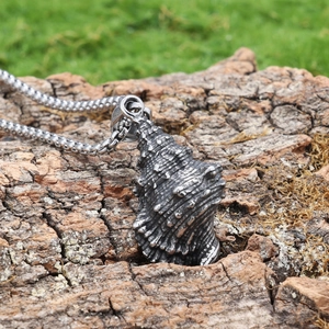 Vintage seashell pendant in stainless steel on tree bark background for biker style