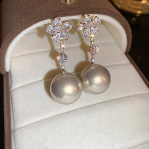 Vue macro de boucles d'oreilles pendantes avec fleur sertie de diamants et perle grise