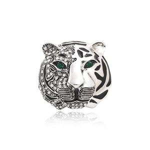 Silver tiger head brooch with green crystal eyes and black enamel details on white background