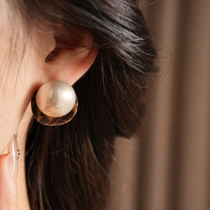 Detailed view of plush leopard print earrings with large pearls on a female model