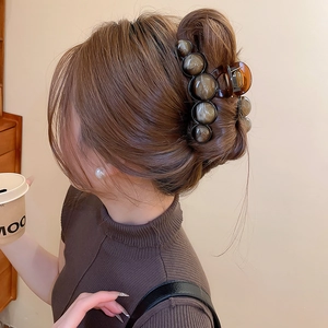 Detail view of brown marble bead hair claw clip holding a classic updo bun