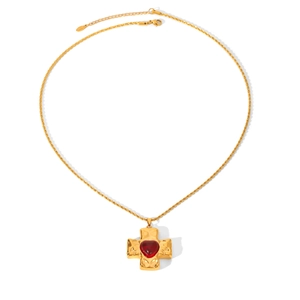 Detail of gold cross pendant with red heart gemstone and hammered texture on chain
