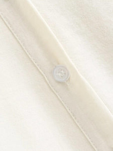 Detailed macro view of cream-colored woven fabric and precise resin button stitching