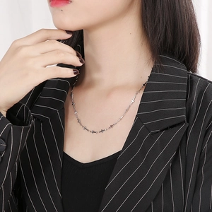 Close-up of a minimalist silver stainless steel necklace with small cross charms on model