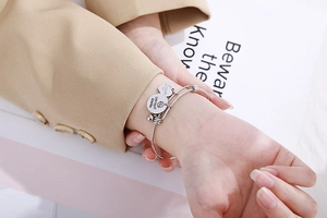 Detailed close-up of adjustable silver heart charm bracelet for grandma on a model's wrist