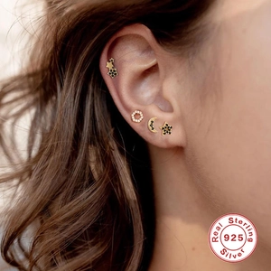 Detailed view of sterling silver gold-plated star and moon stud earrings on ear