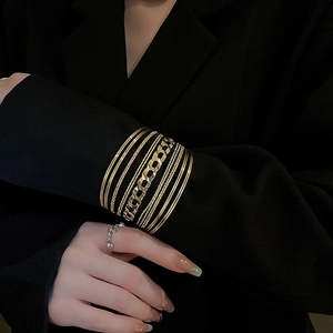Detail of layered gold geometric bangles featuring twisted rope and chain link textures