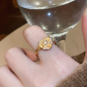 Close-up of a 24K gold plated flower ring with sparkling white zircon stones on a finger