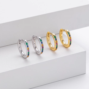 Macro detail of gold and silver S925 earrings with rainbow cubic zirconia on white stands