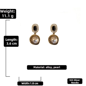 Détail de boucles d'oreilles vintage en alliage doré avec gemmes noires, perles et tiges en argent 925