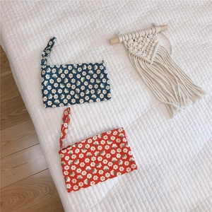Detail of blue and red floral cotton pouches with wristlet and zipper on quilted surface