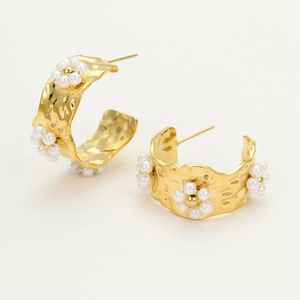 Detail of 18K gold C-shape earrings with hammered texture and pearl flower accents
