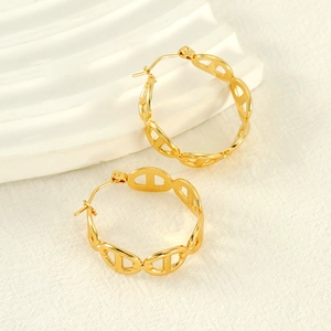 Boucles d'oreilles créoles dorées avec maillons creux sur un support texturé blanc