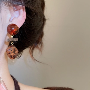 Détail de boucles d'oreilles rétro en bois œil de tigre aux tons marron d'automne