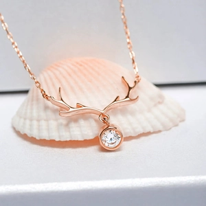 Detailed close-up of rose gold antler pendant with sparkling cubic zirconia on shell background