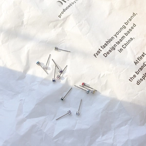 Macro shot of colorful mini birthstone stud earrings on textured white paper