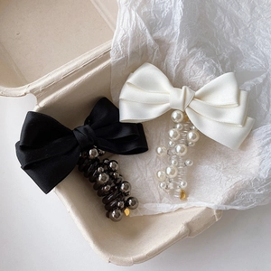 Detail of satin bow hair clips with faux pearls and beads in a textured gift box