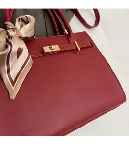 Detail of burgundy tote bag with gold twist lock and decorative heart pattern silk scarf
