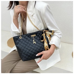 Detailed view of black quilted tote bag with gold deer charm and printed silk scarf