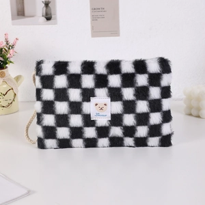 Detail of plush checkered makeup bag with cute bear patch and woven carrying strap