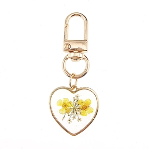 Detail of heart resin keychain featuring real yellow dried flowers and gold clasp
