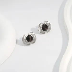 Close-up of silver fan-shaped earrings featuring a round black cat eye stone inlay