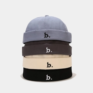 Stapel docker caps in vier kleuren met een klein geborduurd detail van de letter b