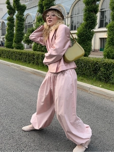 Outdoor shot of a pink satin suit with oversized wide-leg pants and a blazer