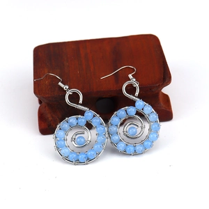 Macro shot of handmade wire wrapped spiral earrings with blue crystals on wood