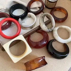 Assorted vintage resin bracelets in marble and amber colors on a wooden tray