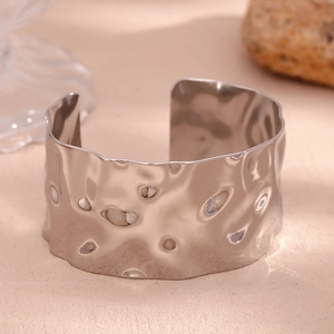 Macro view of wide silver open cuff bracelet with hammered texture and wavy edges