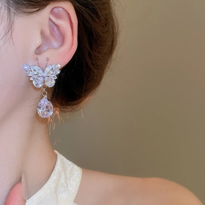 Detail view of silver butterfly earrings with sparkling zircon waterdrop tassels on a model
