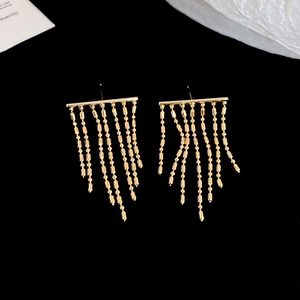 Detail of elegant gold tassel earrings featuring delicate metal beads on dark background