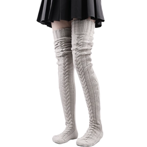 Detailed knit texture of beige over-the-knee leg warmers with cable pattern