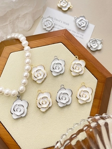 Detail showing white enamel camellia pendants with gold and silver plated edges for DIY