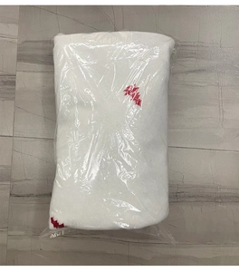 Détail de la jupe de sapin de Noël blanche en fausse fourrure emballée sous sachet plastique