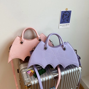 Pink and purple bat-shaped bags with spider web quilting on a silver suitcase