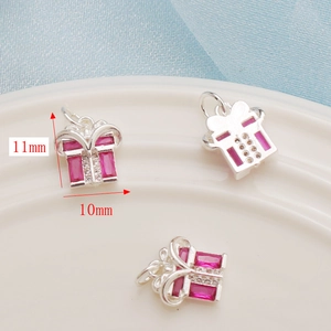 Macro view of 11mm silver gift box charms with pink gemstones and clear crystals