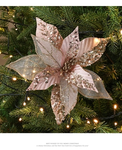Detailed view of pink fabric Christmas flower with gold sequins on a lit festive tree