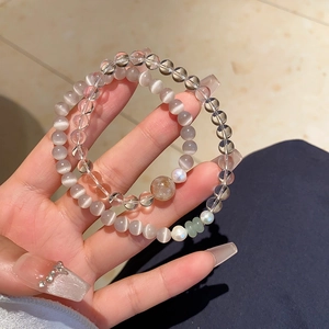 Detail view of stacked crystal bracelets featuring white quartz and cat's eye stone beads