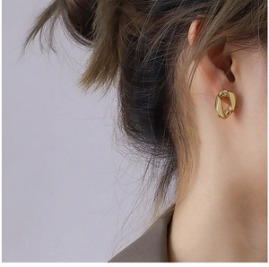 Gros plan d'un mannequin portant des boucles d'oreilles dorées géométriques torsadées