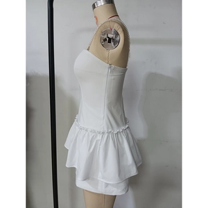 Detail of white backless dress with ruffle hem and delicate pearl straps on a mannequin