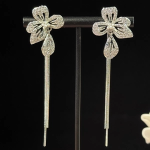 Gros plan détaillé des boucles d'oreilles à pompons argentés avec clous à fleurs et zircons