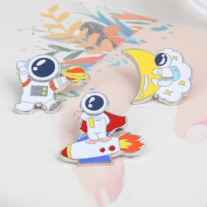 Detail view of 3 astronaut enamel pins featuring planet, rocket, and moon designs