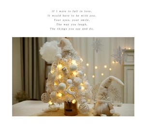 Detail of white flocked mini Christmas tree with warm LED lights and a cute gnome doll